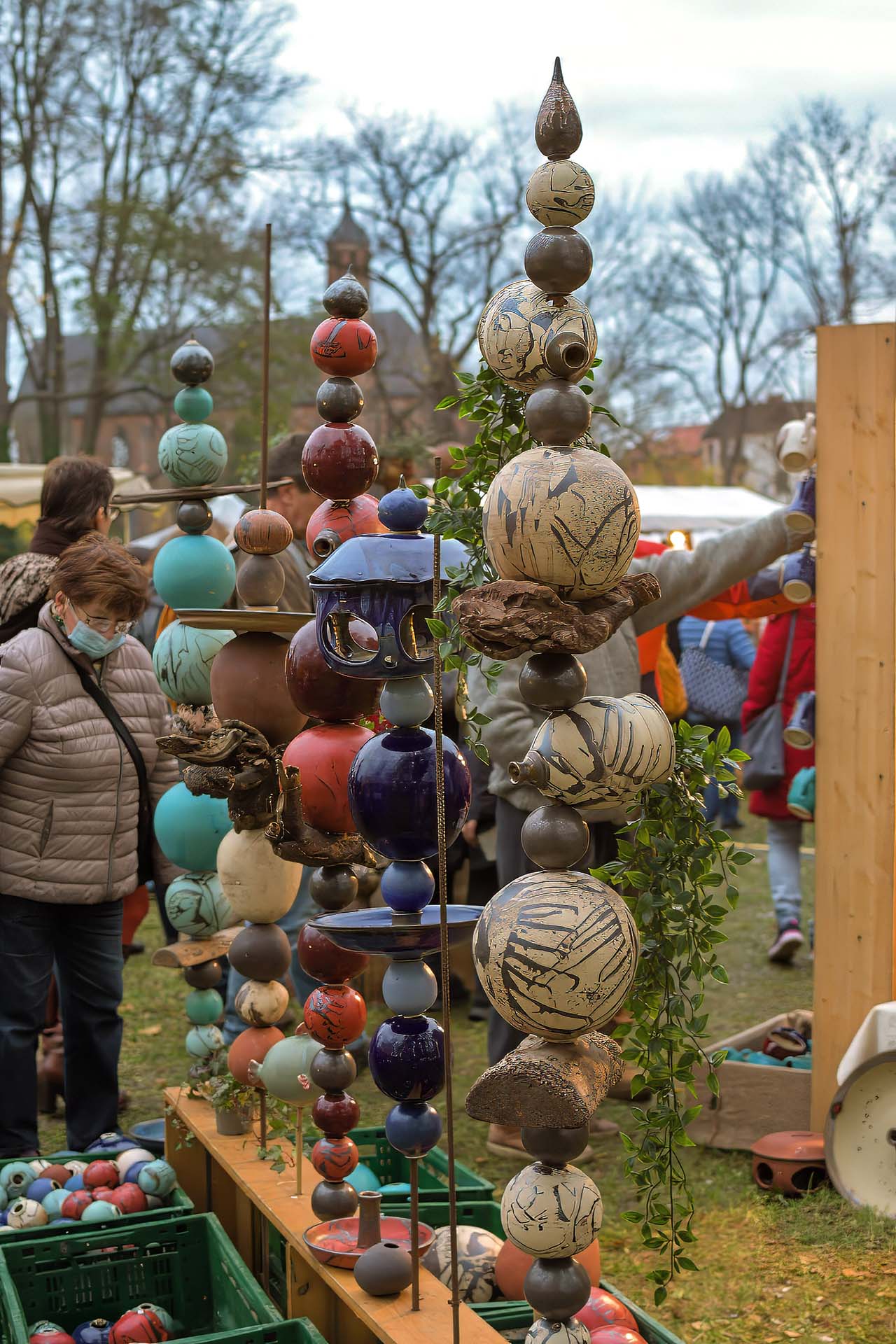 Bunte glasierte Keramikkugeln, aufgereiht als Gartenstelen.