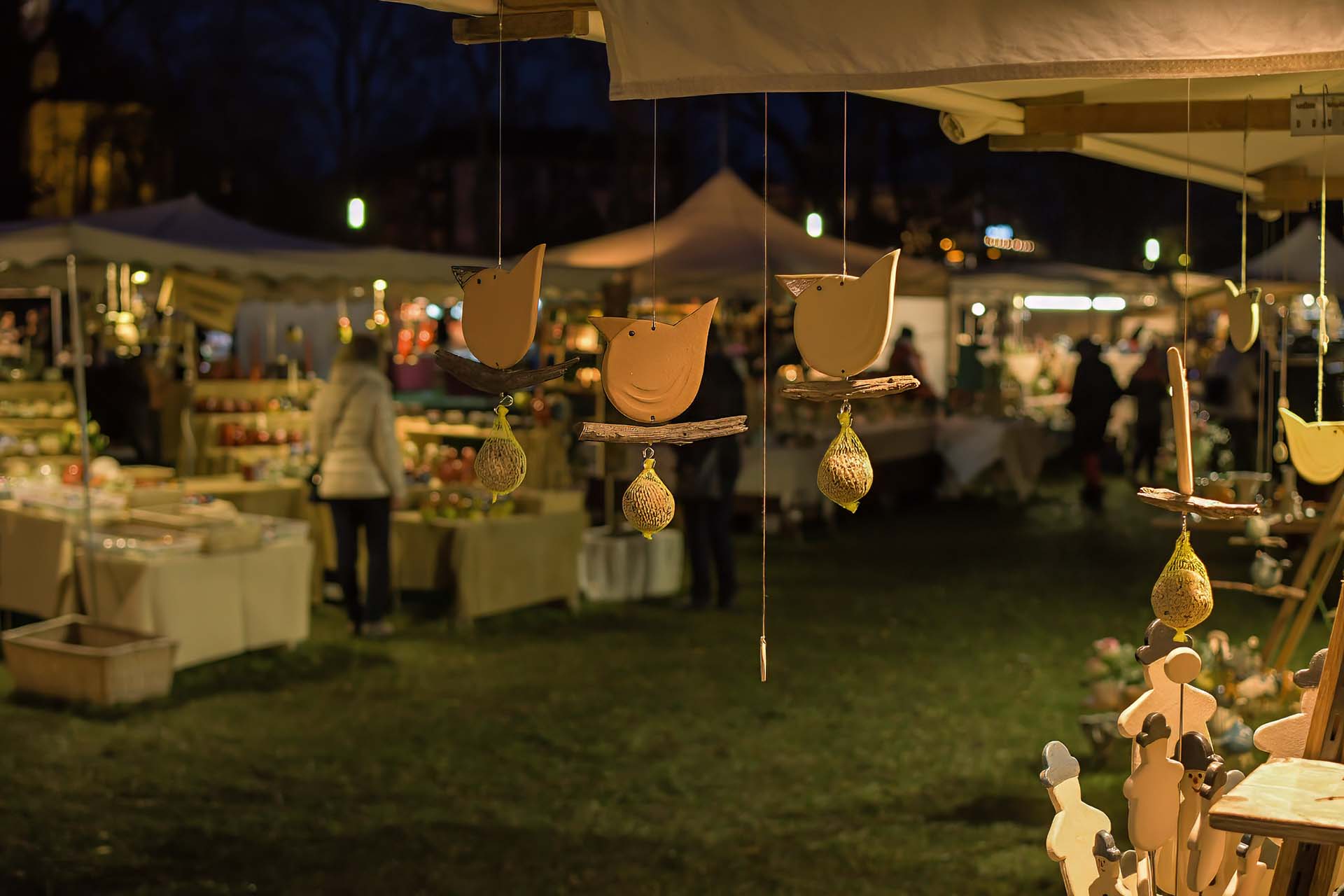 Keramische Vögel als Windspiele vor dem abendlichen Markt.