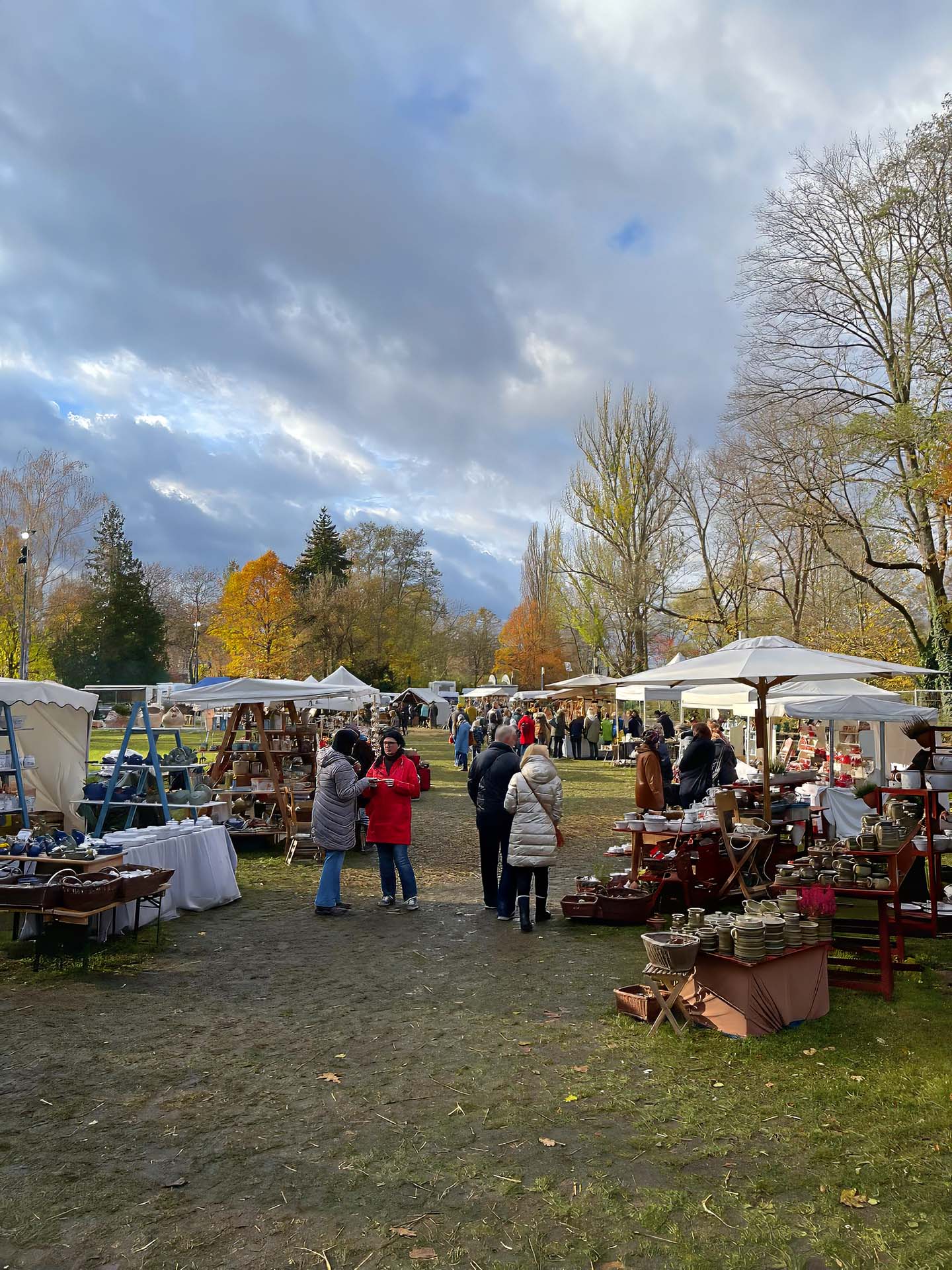 Blick über den Töpfermarkt mit Ständen und Bäumen im Herbstlaub.